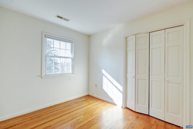 unfurnished bedroom with light hardwood / wood-style flooring and a closet