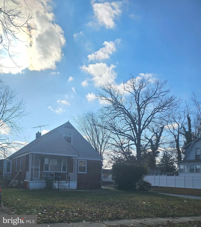 back of property featuring a lawn and covered porch