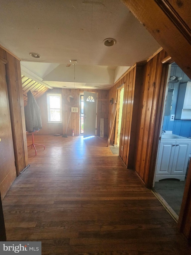 corridor featuring wooden walls, wood finished floors, and vaulted ceiling
