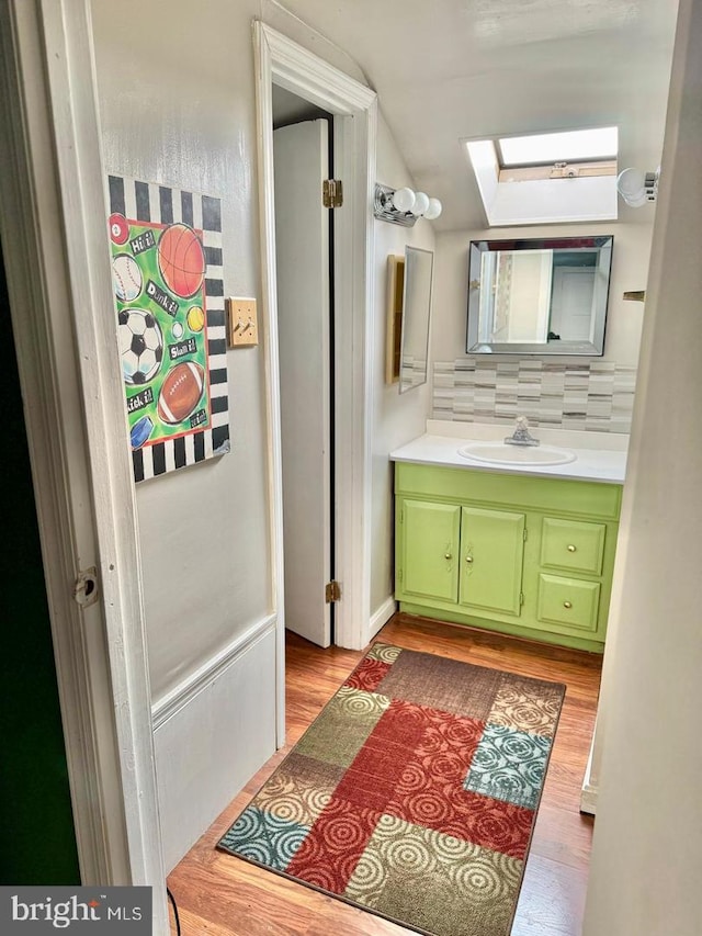 bathroom featuring vanity, backsplash, hardwood / wood-style flooring, and a skylight