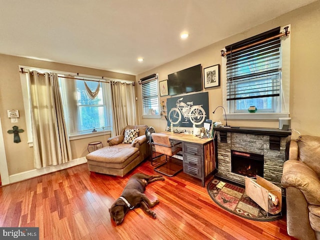 living area with a stone fireplace and light wood-type flooring