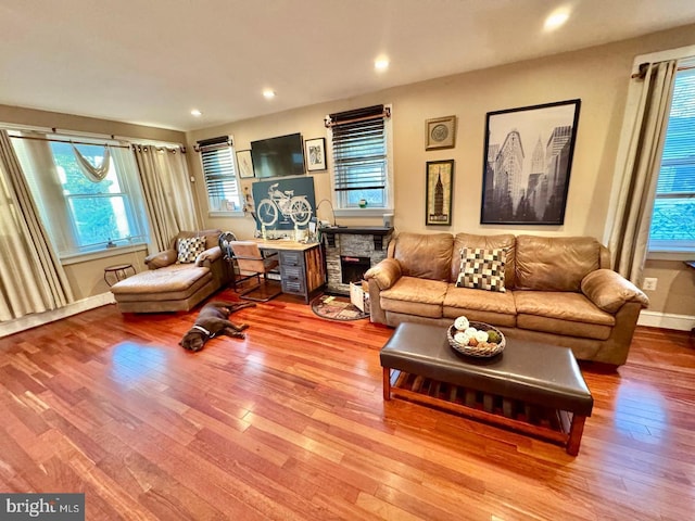 living room with hardwood / wood-style floors and a stone fireplace