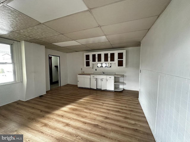 kitchen with hardwood / wood-style flooring, a paneled ceiling, white cabinets, and sink