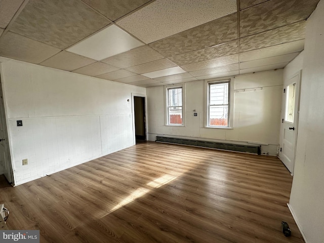 spare room with hardwood / wood-style floors, a paneled ceiling, and a baseboard heating unit