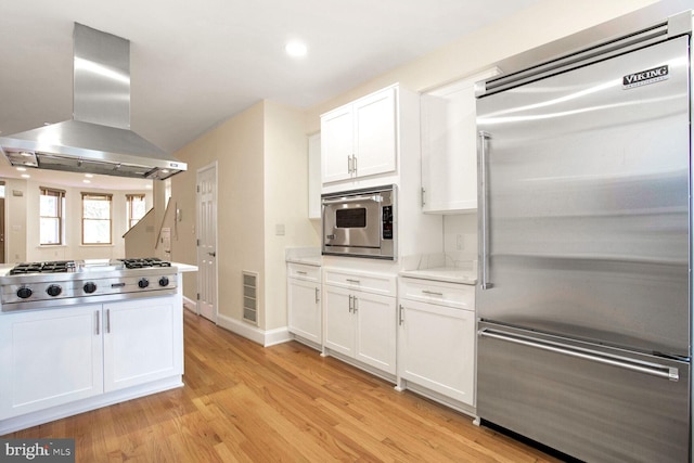 kitchen with white cabinetry, built in appliances, island range hood, and light hardwood / wood-style floors