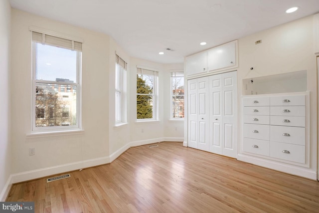 unfurnished bedroom with light wood-type flooring and a closet