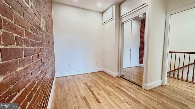 interior space featuring light wood-type flooring and brick wall