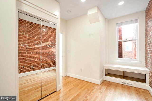 interior space with light hardwood / wood-style flooring, a closet, and brick wall