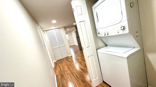 laundry room with stacked washing maching and dryer and light hardwood / wood-style floors