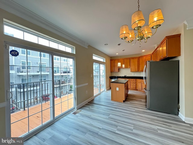 kitchen with a center island, decorative light fixtures, a notable chandelier, light hardwood / wood-style floors, and stainless steel refrigerator