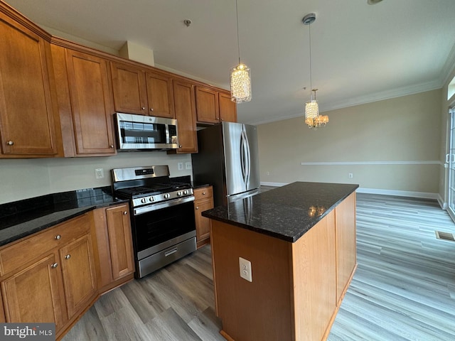 kitchen with a center island, hanging light fixtures, light hardwood / wood-style flooring, crown molding, and appliances with stainless steel finishes