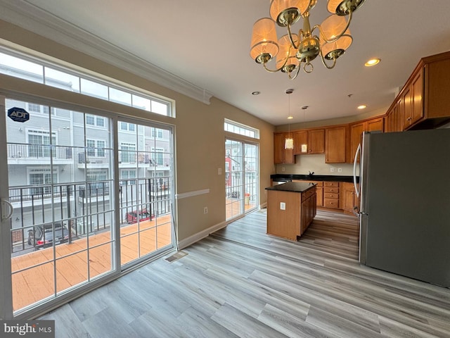 kitchen featuring hanging light fixtures, light hardwood / wood-style flooring, stainless steel fridge, a chandelier, and a kitchen island