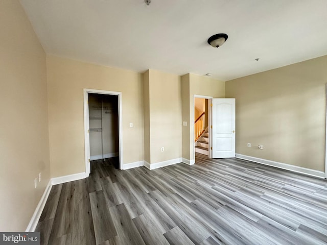 unfurnished bedroom with hardwood / wood-style flooring, a spacious closet, and a closet