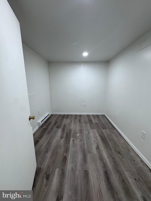 empty room with dark hardwood / wood-style flooring, baseboard heating, and ornamental molding