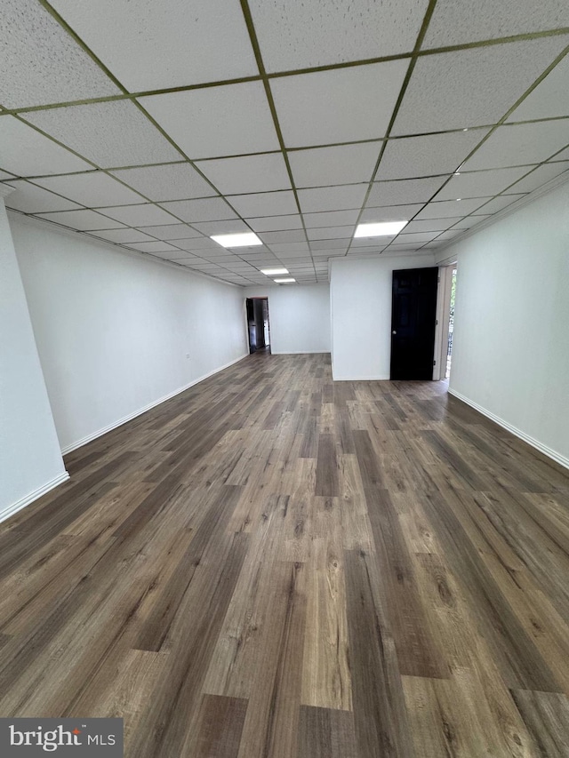 basement featuring a paneled ceiling and dark hardwood / wood-style floors