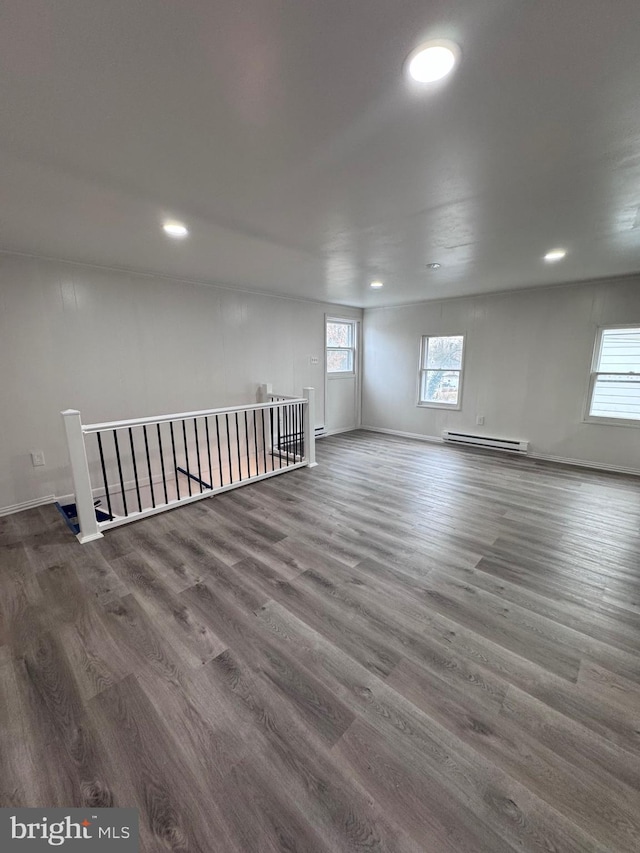 unfurnished room featuring dark hardwood / wood-style flooring, a baseboard radiator, and a wealth of natural light