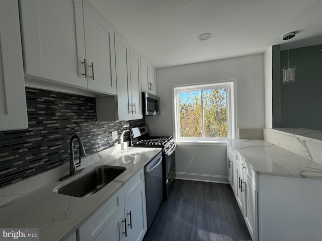 kitchen featuring light stone countertops, stainless steel appliances, sink, decorative light fixtures, and white cabinetry