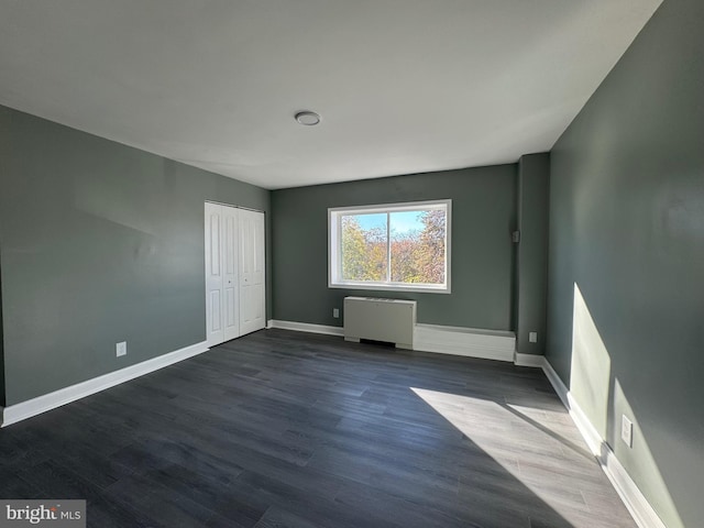 spare room with dark hardwood / wood-style flooring and radiator