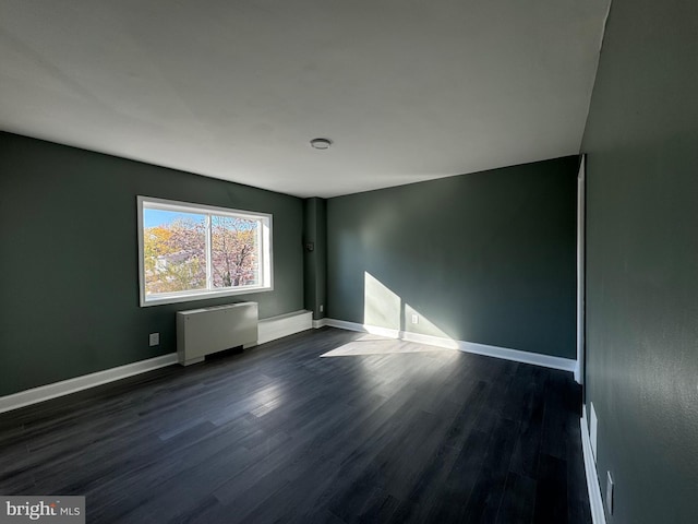 empty room with radiator heating unit and dark wood-type flooring