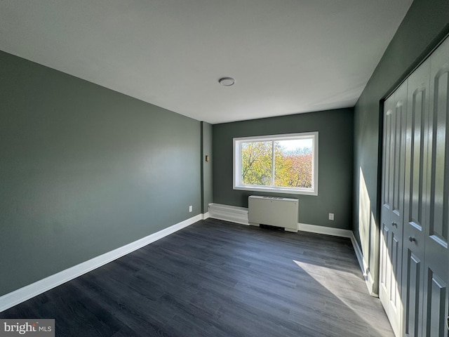 unfurnished bedroom with hardwood / wood-style flooring and radiator