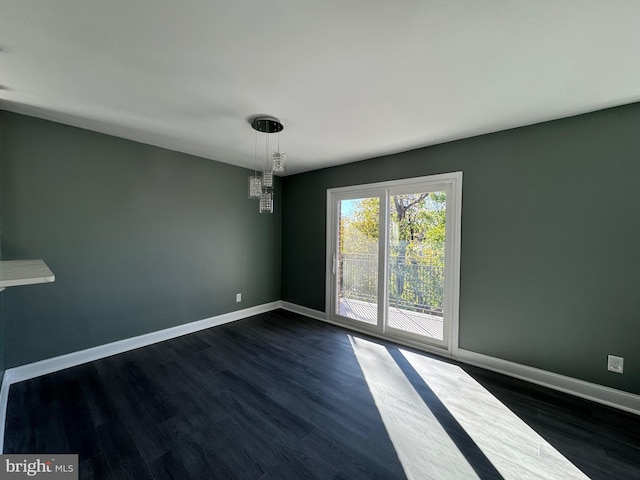 unfurnished room featuring dark wood-type flooring and a chandelier