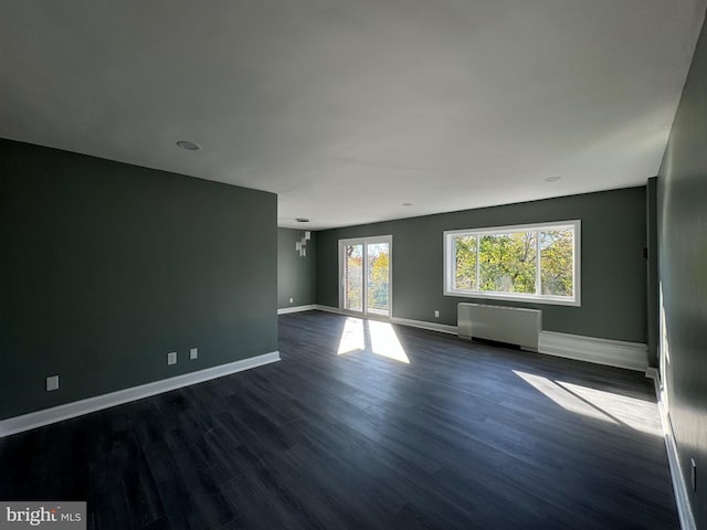 spare room with a chandelier, radiator heating unit, and dark hardwood / wood-style floors