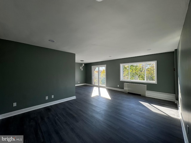 unfurnished room with radiator heating unit, dark wood-type flooring, and a chandelier