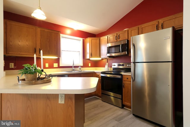 kitchen featuring lofted ceiling, sink, appliances with stainless steel finishes, decorative light fixtures, and light hardwood / wood-style floors