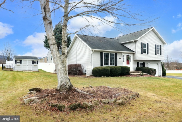 tri-level home featuring a garage, an outdoor structure, and a front lawn