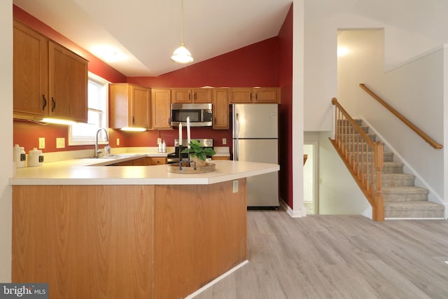 kitchen featuring kitchen peninsula, light wood-type flooring, stainless steel appliances, sink, and pendant lighting