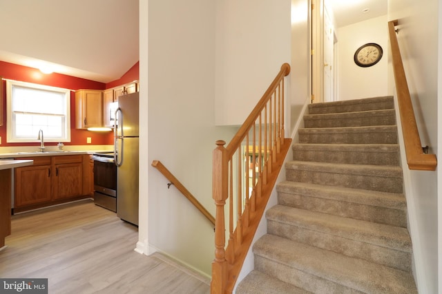 stairway with hardwood / wood-style floors, vaulted ceiling, and sink