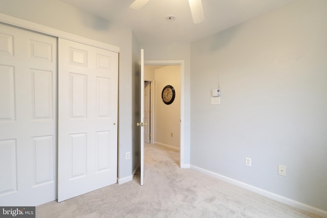 unfurnished bedroom with ceiling fan, light carpet, and a closet