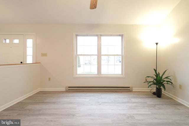 empty room featuring light hardwood / wood-style floors, ceiling fan, and a baseboard heating unit