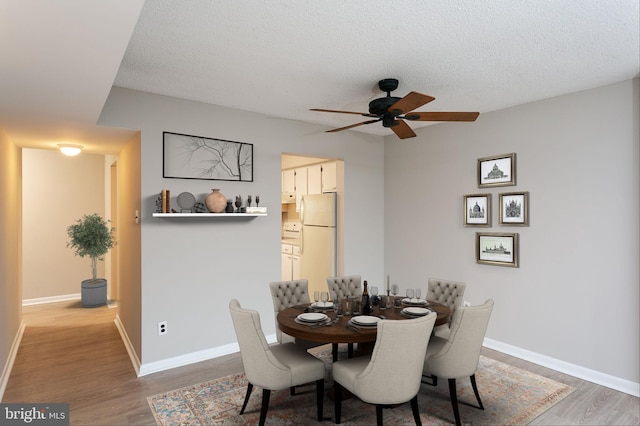 dining area with hardwood / wood-style flooring, a textured ceiling, and ceiling fan