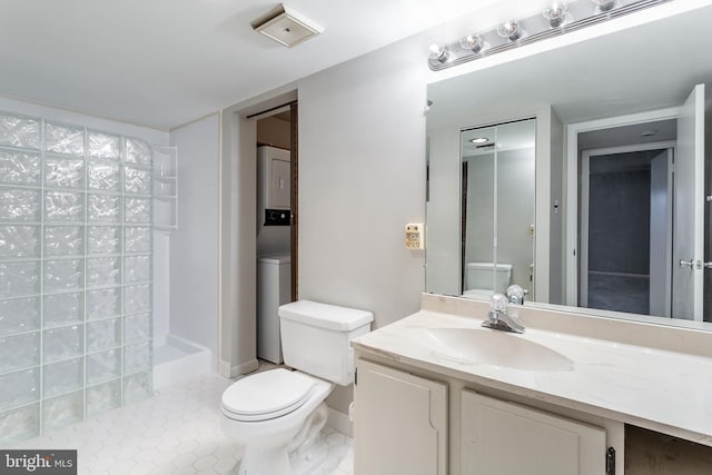 bathroom with walk in shower, stacked washer / drying machine, vanity, and toilet