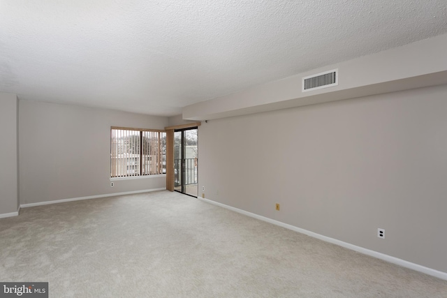 carpeted empty room featuring a textured ceiling