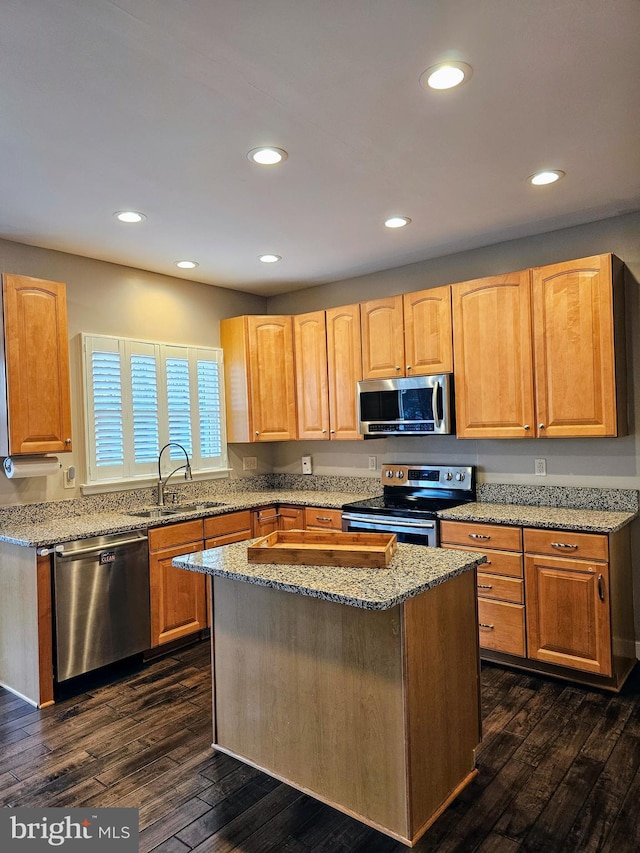 kitchen featuring dark wood-type flooring, sink, light stone counters, a center island, and stainless steel appliances