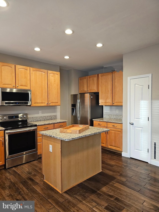 kitchen with a kitchen island, appliances with stainless steel finishes, dark wood-type flooring, and light stone counters