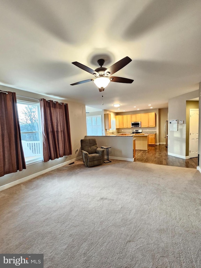 unfurnished living room with dark colored carpet and ceiling fan