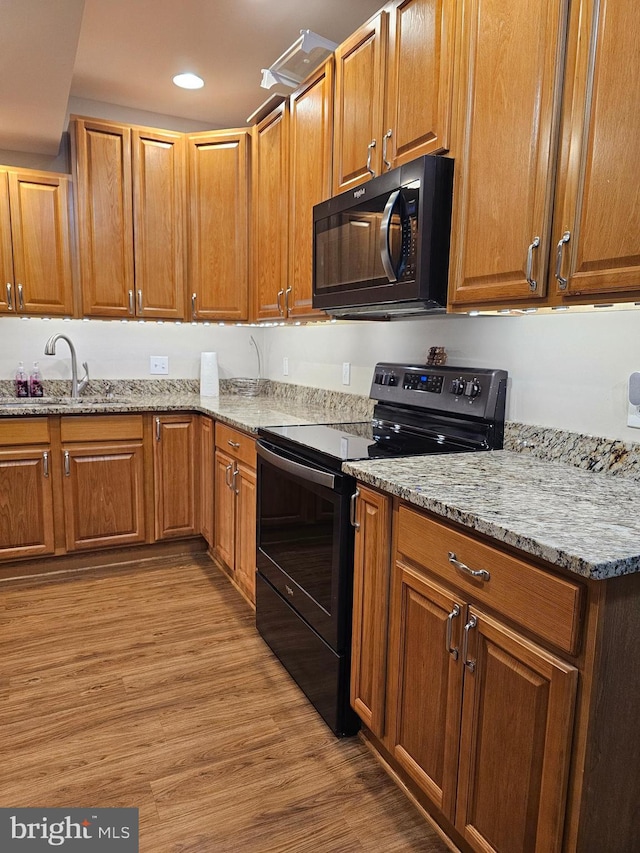 kitchen with sink, light stone countertops, black range with electric cooktop, and light hardwood / wood-style flooring