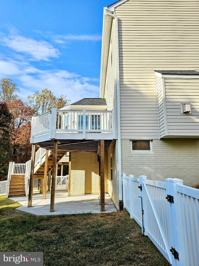 view of side of home with a deck, a patio area, and a lawn