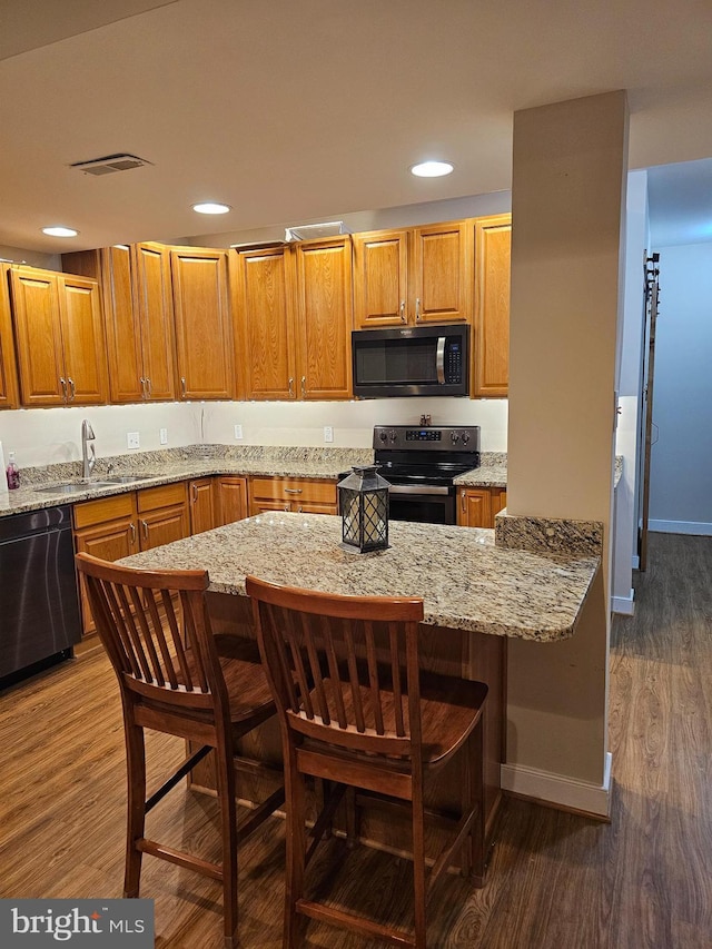 kitchen featuring range with electric stovetop, dishwasher, dark wood-type flooring, and a kitchen bar