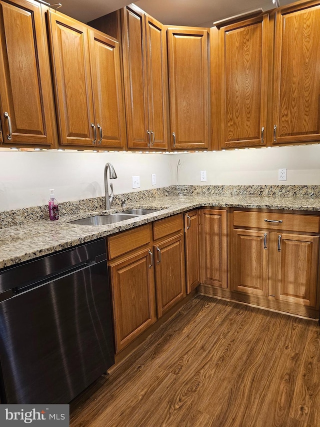 kitchen with dark wood-type flooring, dishwasher, sink, and light stone countertops