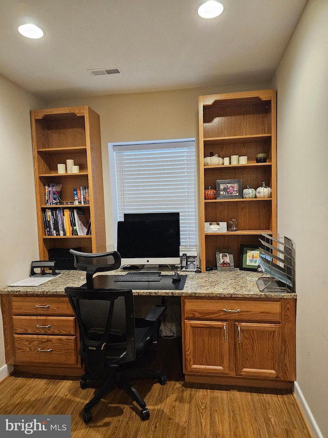 home office with built in desk and light hardwood / wood-style floors