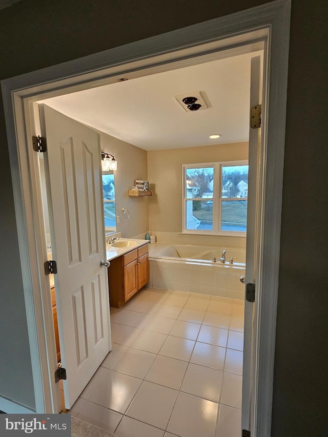 bathroom featuring vanity, tiled tub, and tile patterned flooring