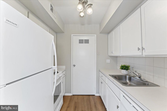 kitchen featuring tasteful backsplash, white appliances, sink, hardwood / wood-style flooring, and white cabinetry