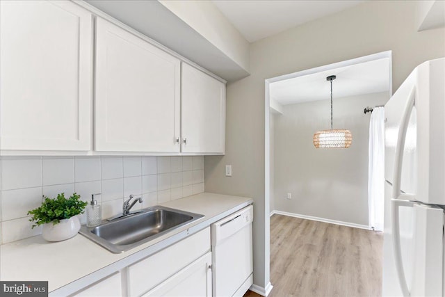 kitchen with white appliances, backsplash, sink, hanging light fixtures, and light wood-type flooring