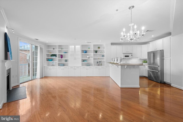 kitchen with hanging light fixtures, a kitchen island, a kitchen bar, white cabinetry, and stainless steel refrigerator