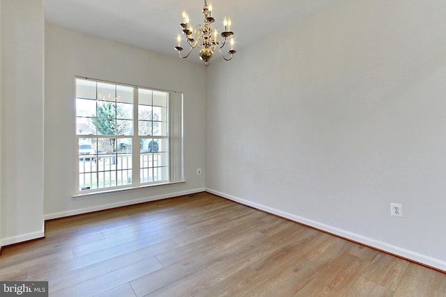 empty room with light hardwood / wood-style flooring and an inviting chandelier