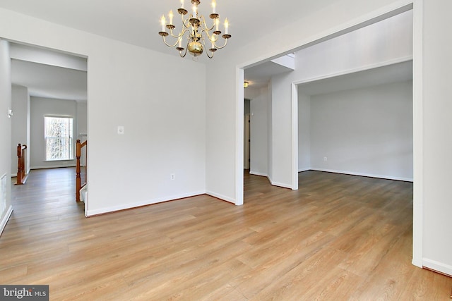 empty room with a chandelier and light wood-type flooring